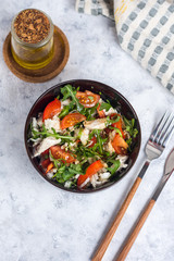 Salad with chicken, tomatoes and spinach with Beijing cabbage in a dark bowl with a napkin, butter and devices on a light background