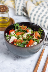 Salad with chicken, tomatoes and spinach with Beijing cabbage in a dark bowl with a napkin, butter and devices on a light background