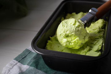 Green diet Ice cream from avocado in a metal tray on a light background. Close-up image