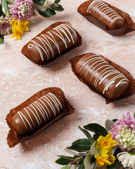 Chocolate pop cake with pink and yellow spring flowers on a marble background.  