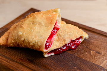Sliced homemade strudel pie with cherry filling close-up on a dark wooden cutting board horizontal.