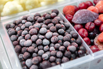 Frozen black currants, berries sprinkled in a plastic tray. Close-up photo.