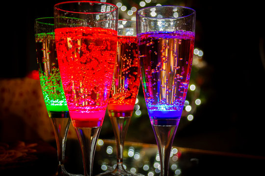 Colorful party glasses, red, blue and green, filled with champagne, cava or prosecco, on a dark and black background. Ready for bubbles and celebration. 