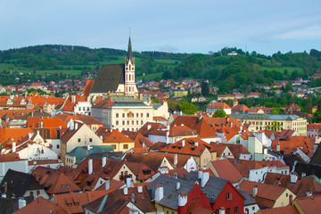 View of the village of Cesky Krumlov and green hill from the Castle, with St. Vitus Church at the background, in Czech Republic
