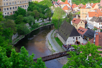 Fototapeta na wymiar Aerial view of the traditional colorful houses of Cesky Krumlov and Vltava river with Lavka pod Zamkem (the bridge underneath the Castle), in Czech Republic