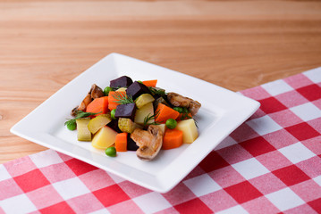 Vegetable stew salad with carrot, pickles, green beans, mushrooms and beetle served in a white plate over wooden table.