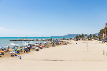 Fototapeta na wymiar Torrenostra beach, Spain. Beautiful beach resort on the mediterranean coast near Valencia. Sunny summer day, blue sky & crowded beach. 