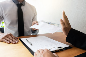 The businessman receiving bribe money in a white envelope form another man at the office