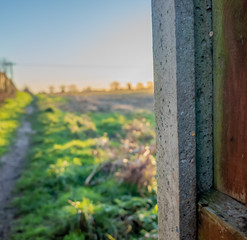  Selective focus of concrete post and wooden fence panel with an out of focus arable field in the background