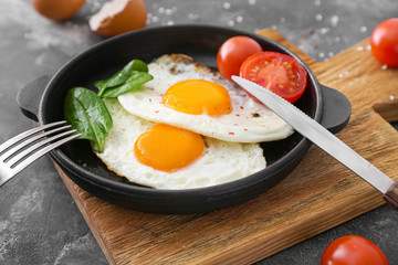 Frying pan with tasty eggs on table