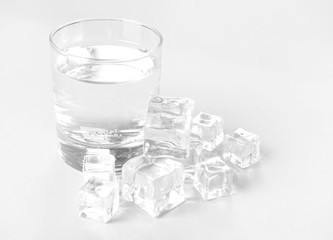 Glass of clean water and ice cubes on light background