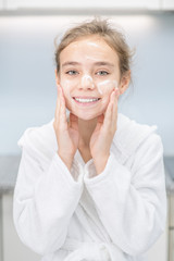 Beautiful young girl washes her face in bathroom at home