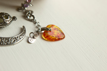 amber heart pendant, jewelry, jewelry lies on a white wooden table, copyspace