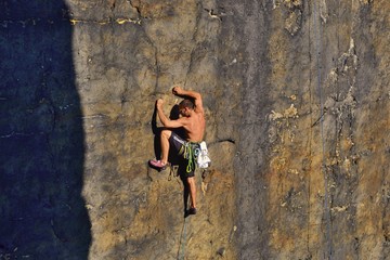 Young man is climbing on the sandstone rock in Sachsen Switzerland. Beautiful autumn day in Germany.