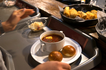 man puts borsch with donuts on his tray in the dining room