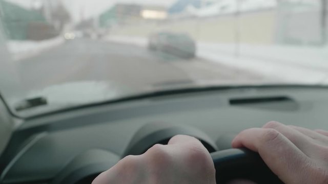 Close up of man's hands on steering wheel. Positions of fingers are changing. Driver's habbits during driving. Blurred view of road through windscreen.