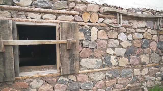 Old traditional classic village house with stone and wooden walls. Rock floor. Wall painted with white lime. There are materials made of wood in the garden. Home historic historical real rural poor. P