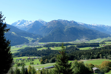 Panorama of Austrian villages, Hollersbach, Passthurn, Oberpinzgau and coniferous forest in Salzach Valley Austria. Snow capped mountain ranges and High Tauern National Park is in the background.