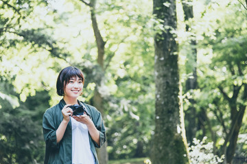 緑の豊かな公園で写真を撮る若い女性