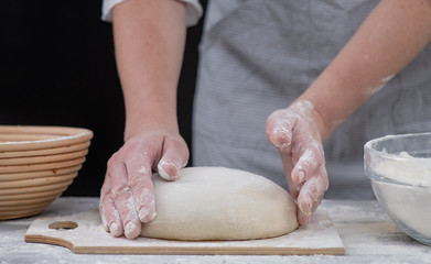 Fototapeta premium Closeup female hands hold the dough. Baker forms homemade bread