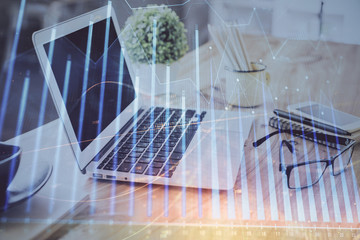 Stock market graph on background with desk and personal computer. Multi exposure. Concept of financial analysis.