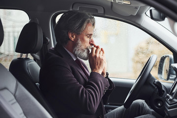 Fashionable senior man in elegant clothes is in the modern car