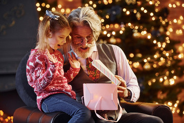 Cheerful fashioned senior man with grey hair and beard with little girl with gift box