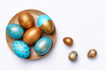 Blue and golden modern easter eggs on a wooden plate. White background.
