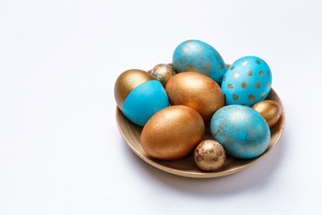 Blue and golden modern easter eggs on a wooden plate. White background.