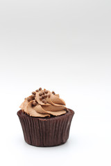 Isolated chocolate cupcake with cream top and crispy topping on a white background