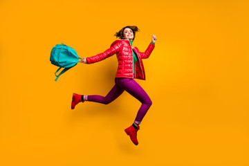 Fototapeta na wymiar Full length profile side photo of cheerful funky youth girl jump run college work day hold blue backpack wear purple shine stylish trendy clothes red boots isolated yellow color background
