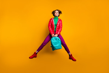 Fototapeta na wymiar Full size photo of cheerful funky fun youth scholar girl jump hold blue backpack enjoy emotions wear purple green pants trousers red boots isolated over bright color background