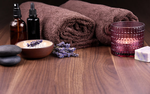 Spa and wellness lavender still life on a wooden background stock images. Spa and wellness setting. Bath salt, brown towels, cosmetic phials, lava stones, lavender and soap stock images