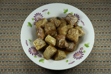 Deep fried cutting taro in syrup (sugar) on the plate. Traditional sweet dessert in Chinese ancestor ceremony or Chinese New year. Famous luxury menu in restaurant. 