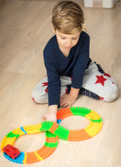 Little boy making trail while playing with car toy on the floor.