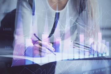 Double exposure of hands making notes with forex chart huds. Stock market concept.