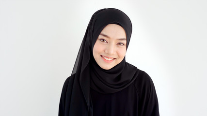 Close Up Portrait of a Young Asian Muslim Woman dressing in the traditional Hijab looking at camera smiling confident on a white background