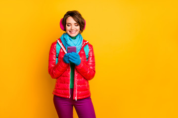 Photo of funny blogger lady walk street looking telephone screen read sms wear casual red coat boots blue scarf gloves ear covers pants isolated yellow color background © deagreez