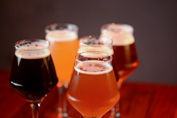Three glasses with different beer on wooden table in a bar. Food photography concept, with copy space
