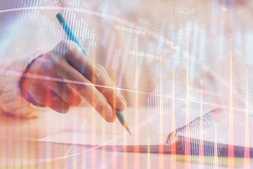 Financial forex graph displayed on hands taking notes background. Concept of research. Double exposure