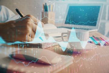 Fototapeta premium Financial chart drawn over hands taking notes background. Concept of research. Double exposure