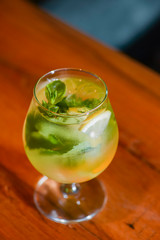 Classic fresh mojito on the table in a bar. Alcohol cocktail with ice, mint and lime on table with blurred background.