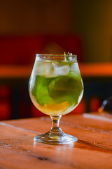 Classic fresh mojito on the table in a bar. Alcohol cocktail with ice, mint and lime on table with blurred background.