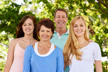 Obraz premium Outdoor family portrait in leafy park of parents and daughters
