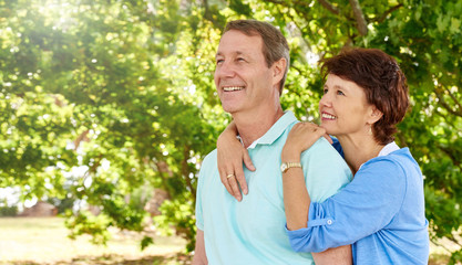 Fototapeta premium Mature husband and wife looking positively up into lush trees