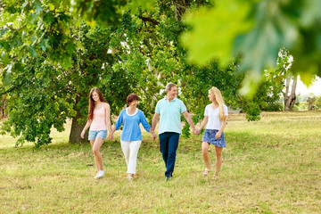 Naklejka premium Laughing family walking hand in hand in a summer park