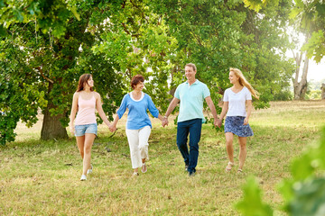 Naklejka na ściany i meble Loving family holding hands and walking in a park