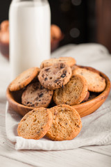 Chocolate chip cookies with milk on burlap and rustic wooden table