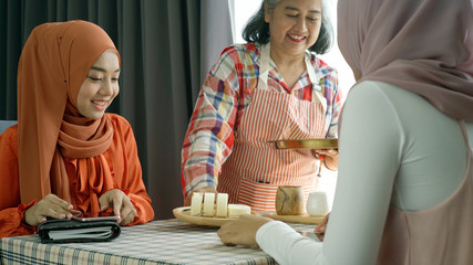 Young beautiful Asian Muslim man and women enjoying a relaxing moment in the coffee shop on a bright sunny day using mobile phone, smartwatch for mobile payment and QR code scan