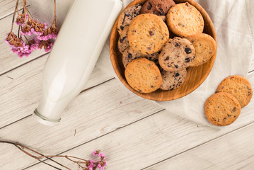 Chocolate chip cookies with milk on burlap and rustic wooden table